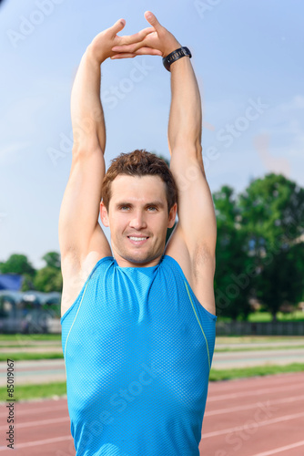 Young sportive man stretching his arms