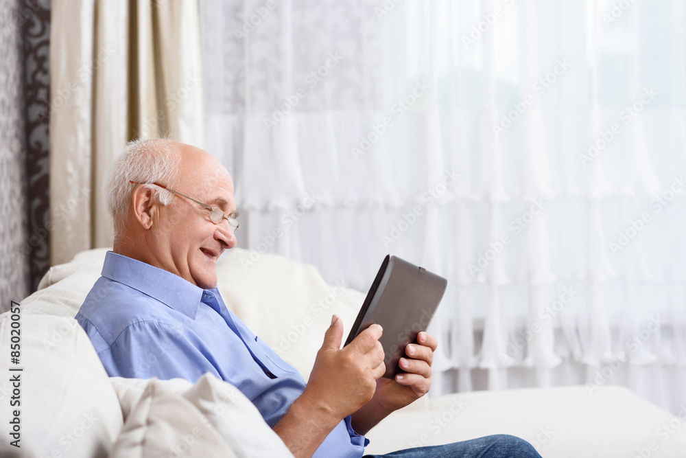 Senior man sitting and holding tablet Senior man sitting and holding tablet