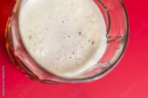 White foam beer close up still on a red background