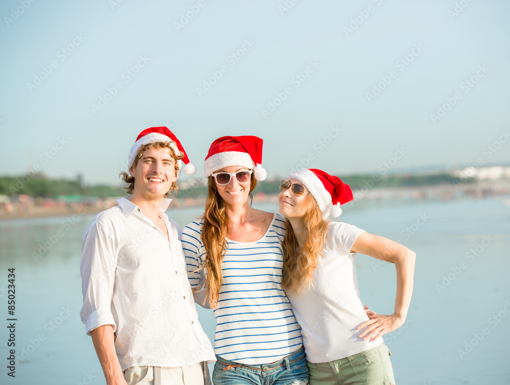 Obraz premium Group of happy young people in christmass hats on the beach