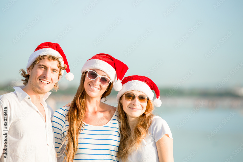 Obraz premium Group of happy young people in christmass hats on the beach