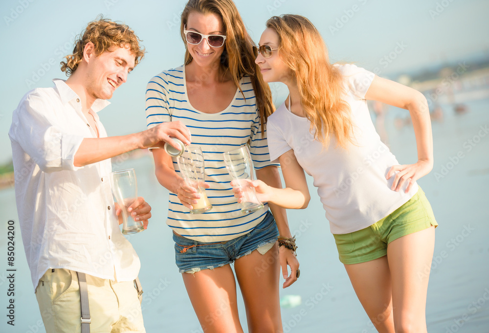 Group of happy young people drinking beer on the beach