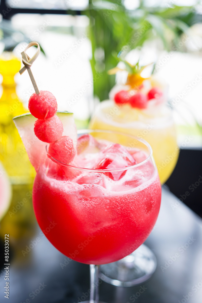 mix of refreshing glass of bright juicy melon and watermalon smoothie or lemonade with ice on a table at a restaurant with the decor of the bright dishes and pieces of melon mix of refreshing glass of bright juicy melon and watermalon smoothie or lemonade with ice on a table at a restaurant with the decor of the bright dishes and pieces of melon