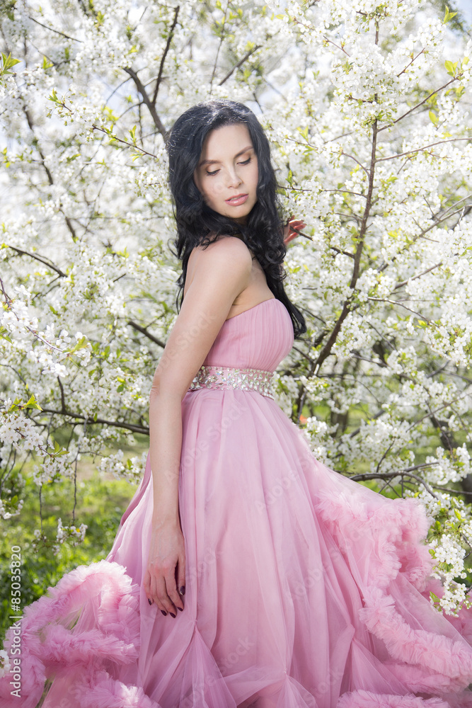 Young woman in the garden of apple blossom