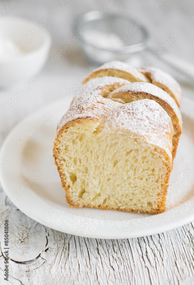 sweet brioche with sugar on a white plate on a light background sweet brioche with sugar on a white plate on a light background