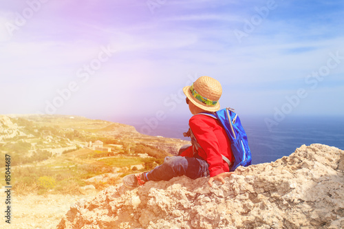 little boy hiking in mountains looking at scenic view