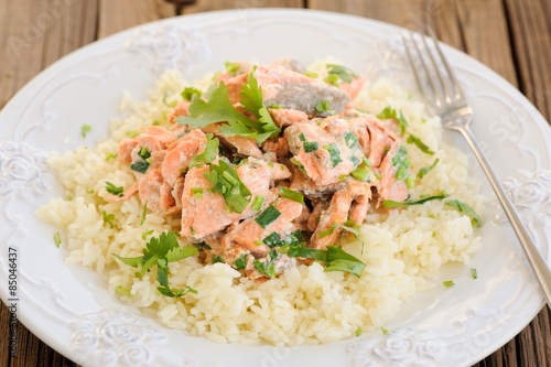 Salmon with rice, scallion and cilantro in white plate with fork