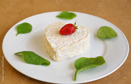 сыр с клубникой и салатом на белой тарелке