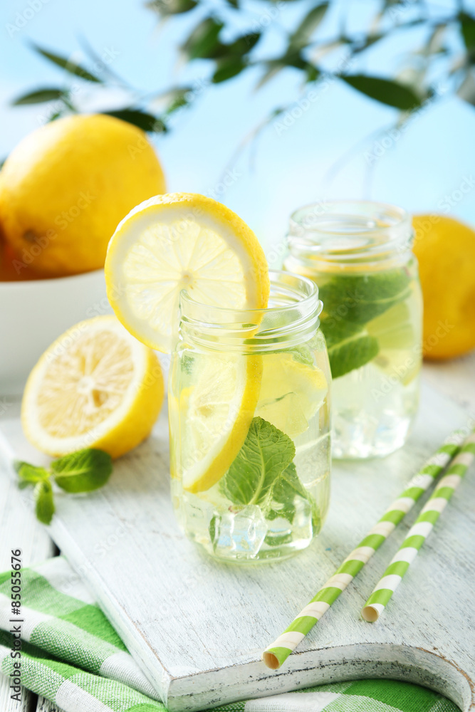 Fresh lemonade with lemon on white wooden background