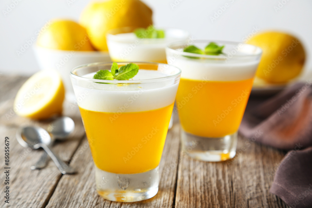 Tasty lemon jelly in glass on grey wooden background