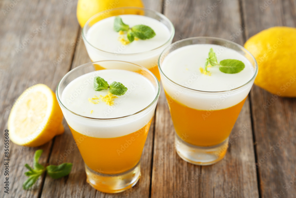 Tasty lemon jelly in glass on grey wooden background Tasty lemon jelly in glass on grey wooden background