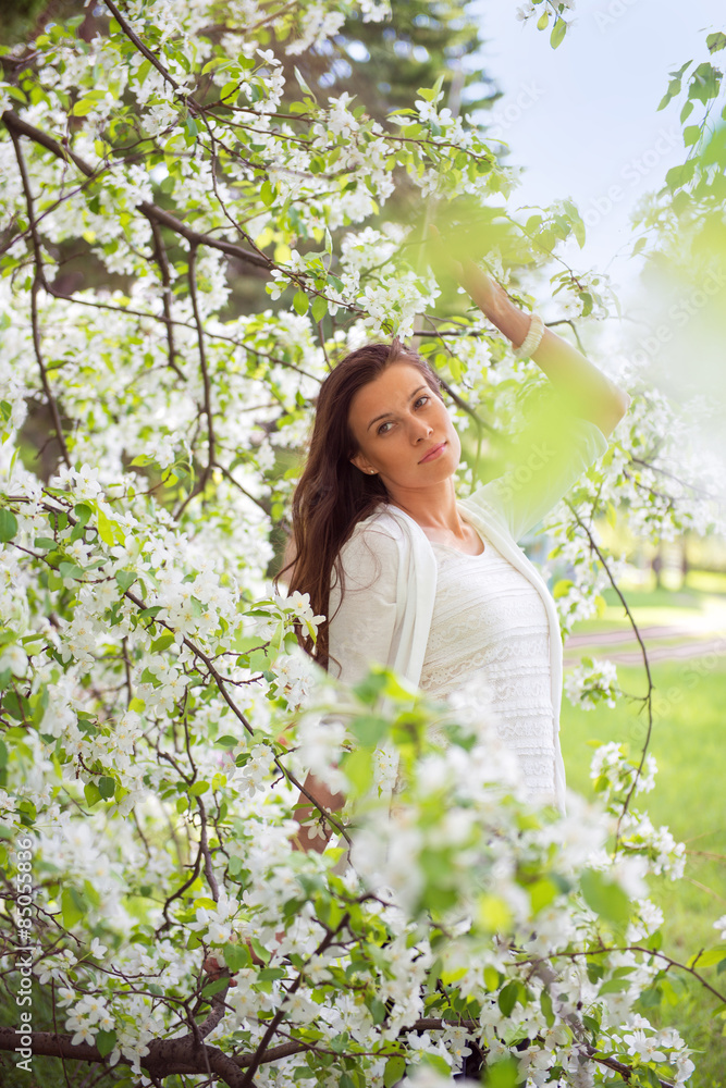 Spring brunette girl standing outdoor in blooming trees. Beautif Spring brunette girl standing outdoor in blooming trees. Beautif