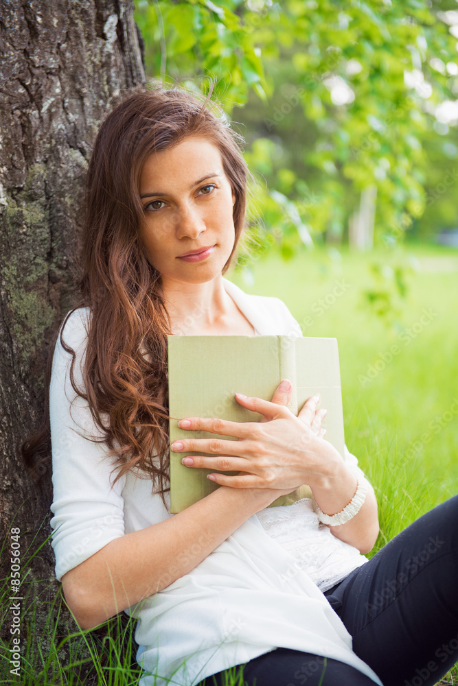 Portrait of spring brunette girl seating outdoor at the tree wit Portrait of spring brunette girl seating outdoor at the tree wit