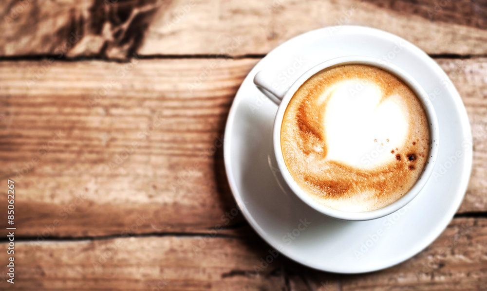 Cup of coffee with heart pattern in a white cup on wooden backgr Cup of coffee with heart pattern in a white cup on wooden backgr