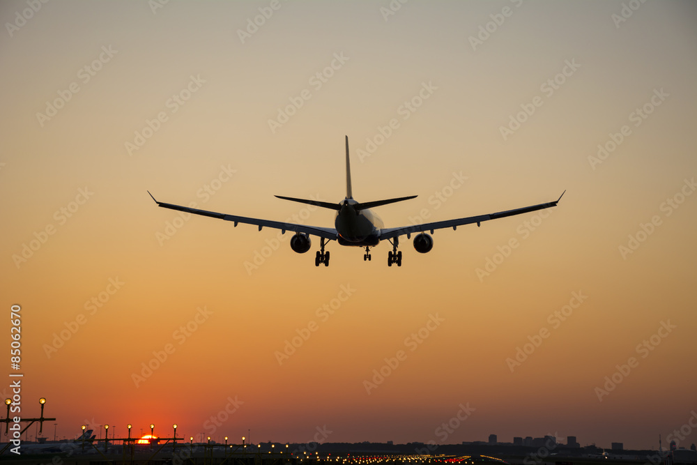 Airplane landing during sunrise.