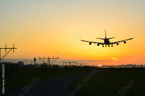 Plane is landing during sunrise.