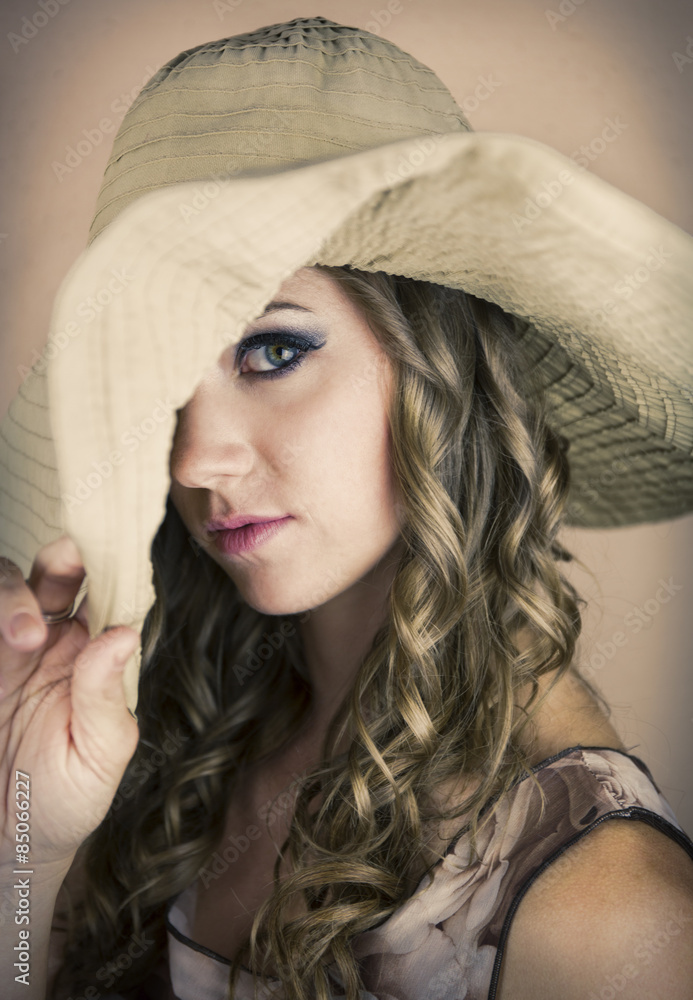 Pretty young woman with big hat pulled over one eye. Pretty young woman with big hat pulled over one eye.