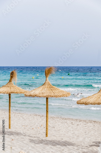 Straw umbrellas on sand beach.