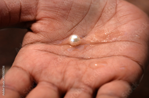 Woman hand holds one big white pink pearl