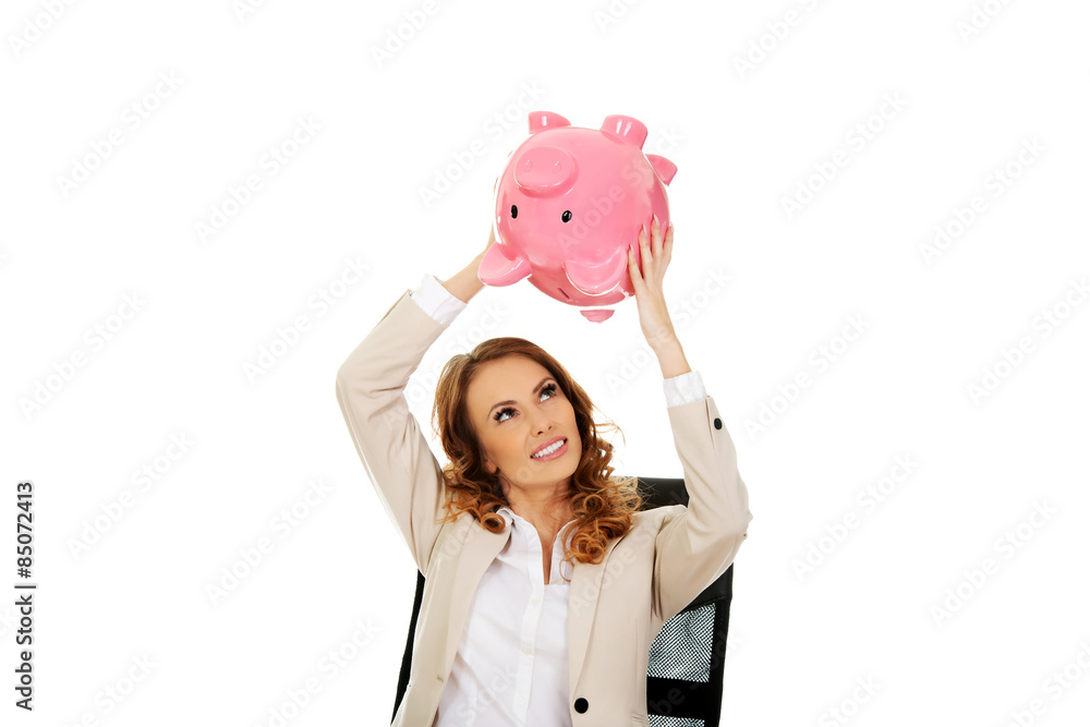 Business woman shaking a piggybank. Business woman shaking a piggybank.