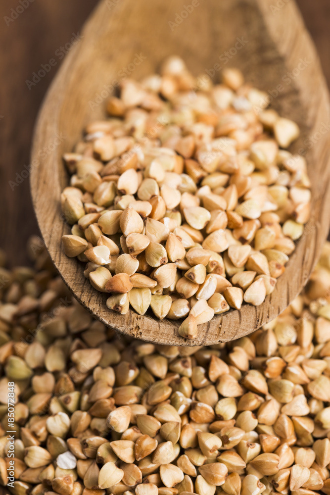 Buckwheat with a spoon on a wooden boards background Buckwheat with a spoon on a wooden boards background