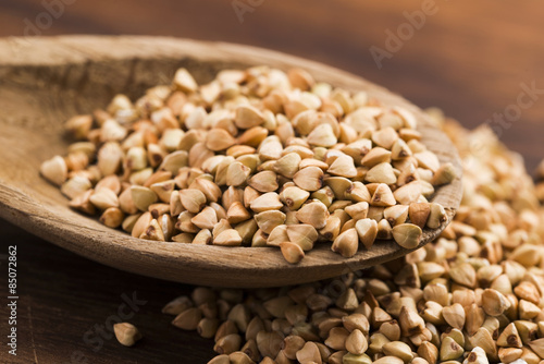 Buckwheat with a spoon on a wooden boards background