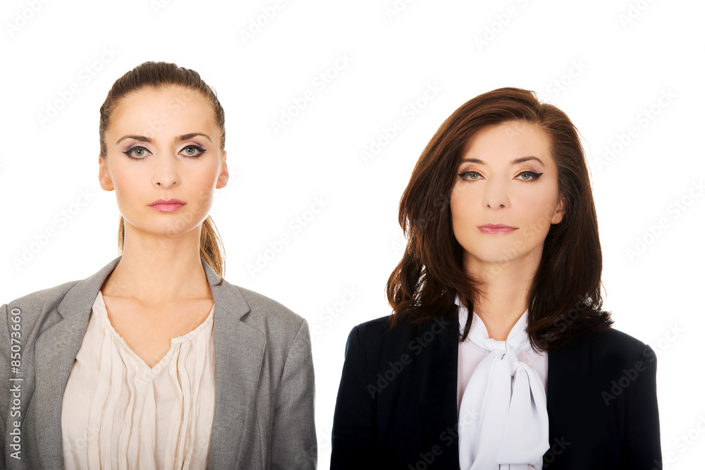 Two women wearing office outfits.