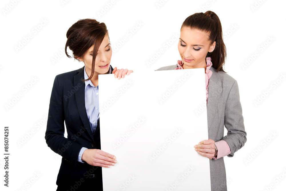 Two businesswomen carrying a big white board. Two businesswomen carrying a big white board.