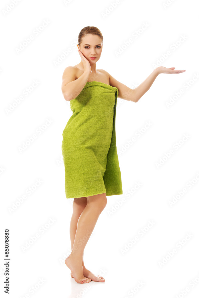 Woman wrapped in towel holding something on palm. Woman wrapped in towel holding something on palm.