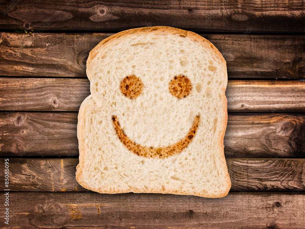 A smile toasted on a slice of bread, on wood background