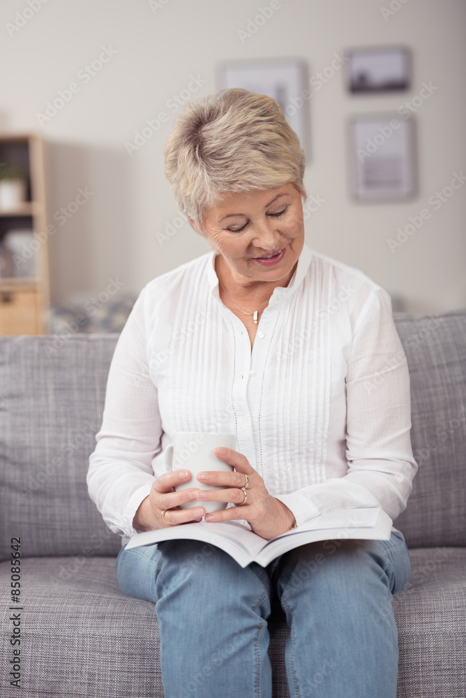 © contrastwerkstatt - moderne seniorin entspannt mit einem buch auf der couch