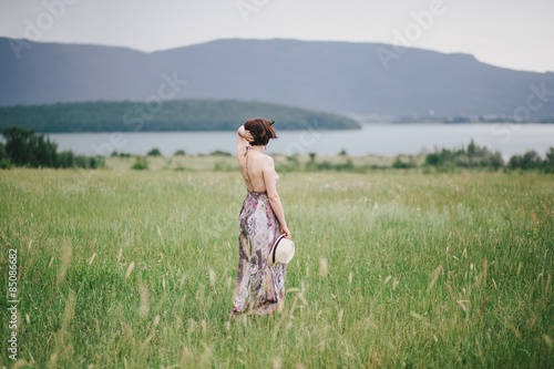 Wallpaper Mural Beautiful hippie woman posing on a green field with mountains and dark clouds on the background.  Torontodigital.ca