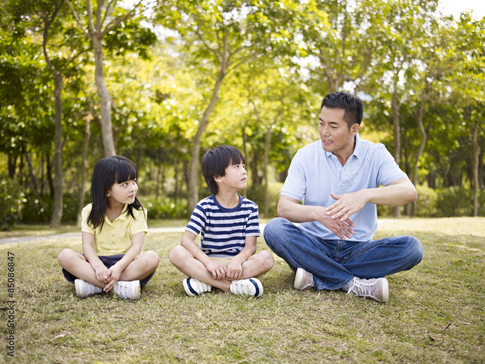 asian father and children talking in park asian father and children talking in park