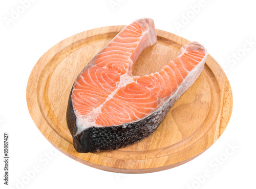Raw salmon steak on cutting board.