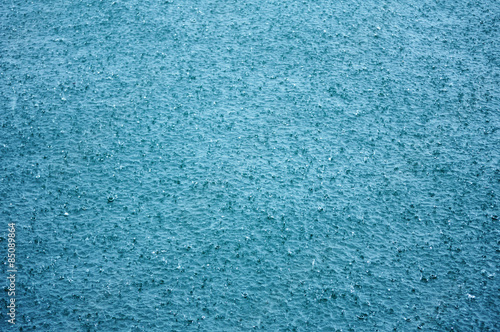 Falling raindrops on a tropical turquoise sea water surface