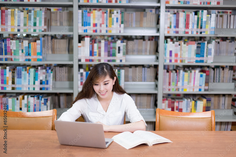 Beautiful asian female student using laptop for study in library Beautiful asian female student using laptop for study in library