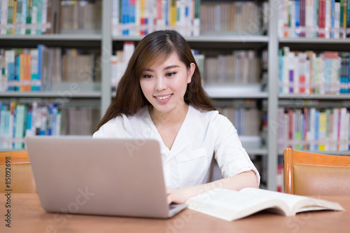 Beautiful asian female student using laptop for study in library