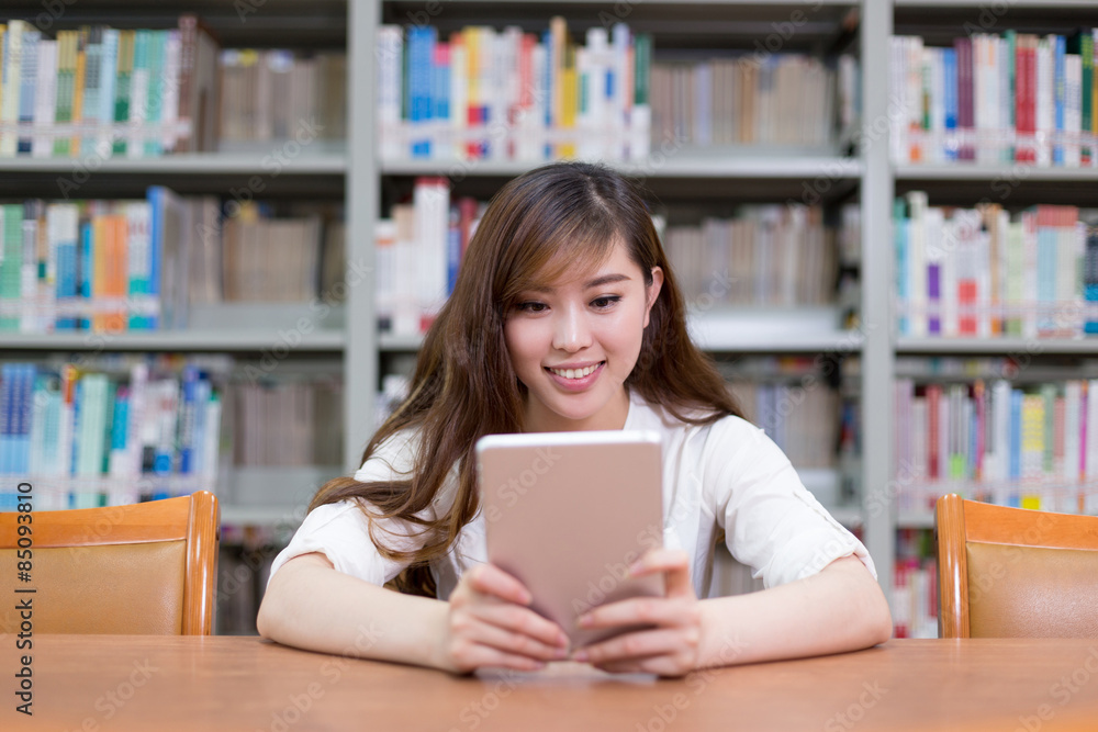 Beautiful asian female student using digital tablet in library Beautiful asian female student using digital tablet in library