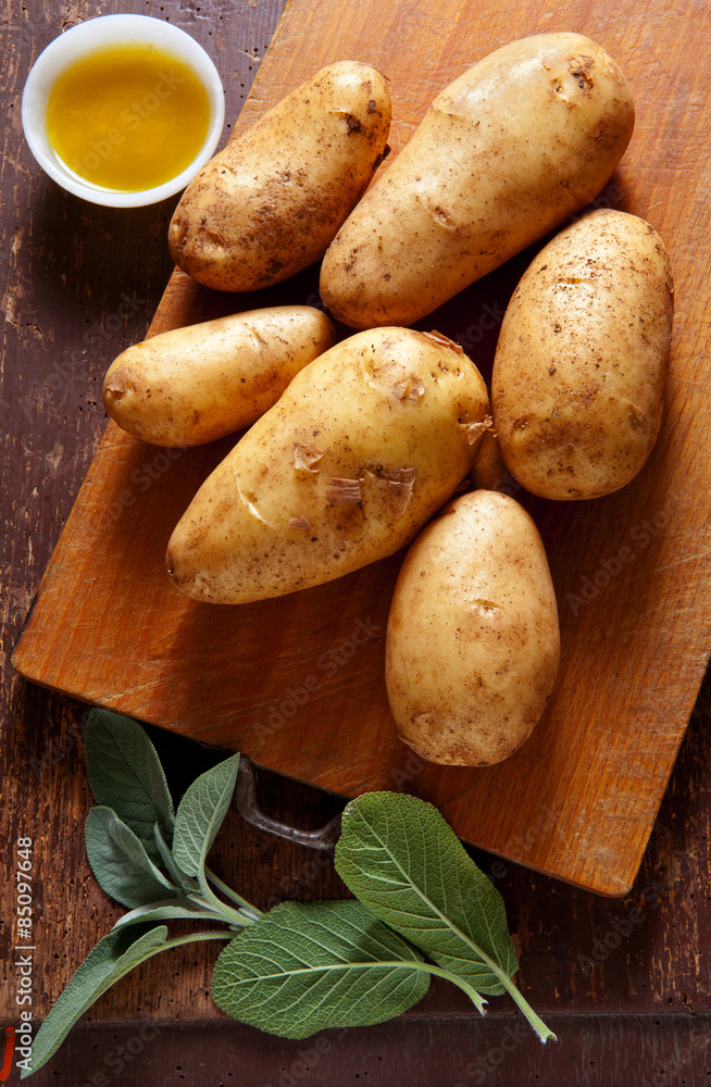 new potatoes on the old wooden background. with sage & olive oil new potatoes on the old wooden background. with sage & olive oil