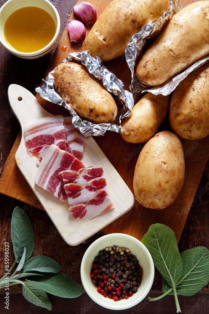 potatoes and sliced bacon on the old wooden background. sage & o potatoes and sliced bacon on the old wooden background. sage & o