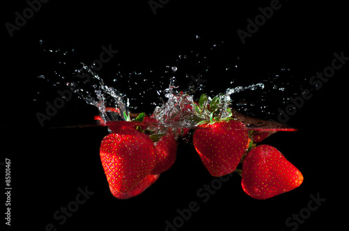Strawberries splashing into water
