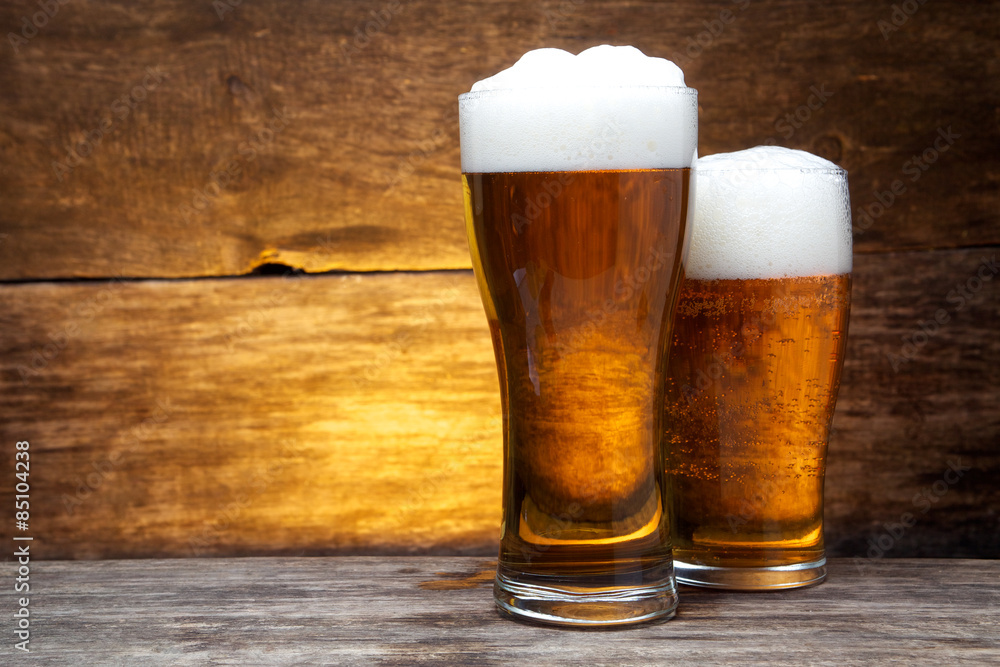 two glasses of beer over vintage wood 