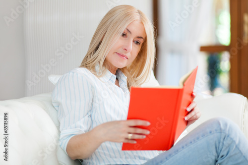 Woman reading a book sitting on a sofa in a living-room