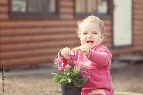 cute baby girl in pink dress puts flowers
