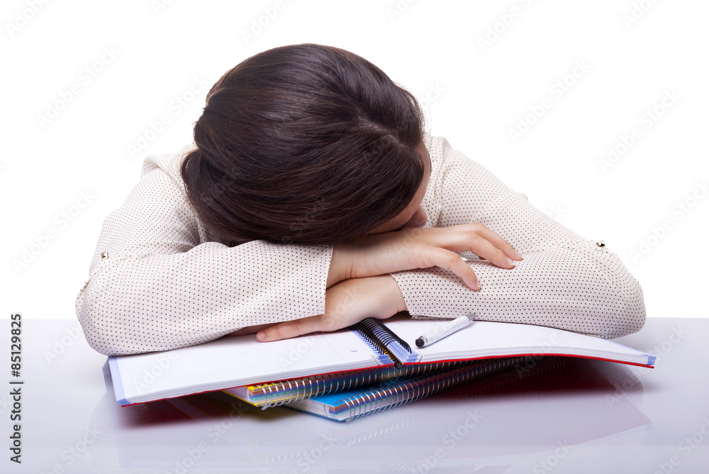 Tired female student sleeping at the desk, isolated on white bac Tired female student sleeping at the desk, isolated on white bac