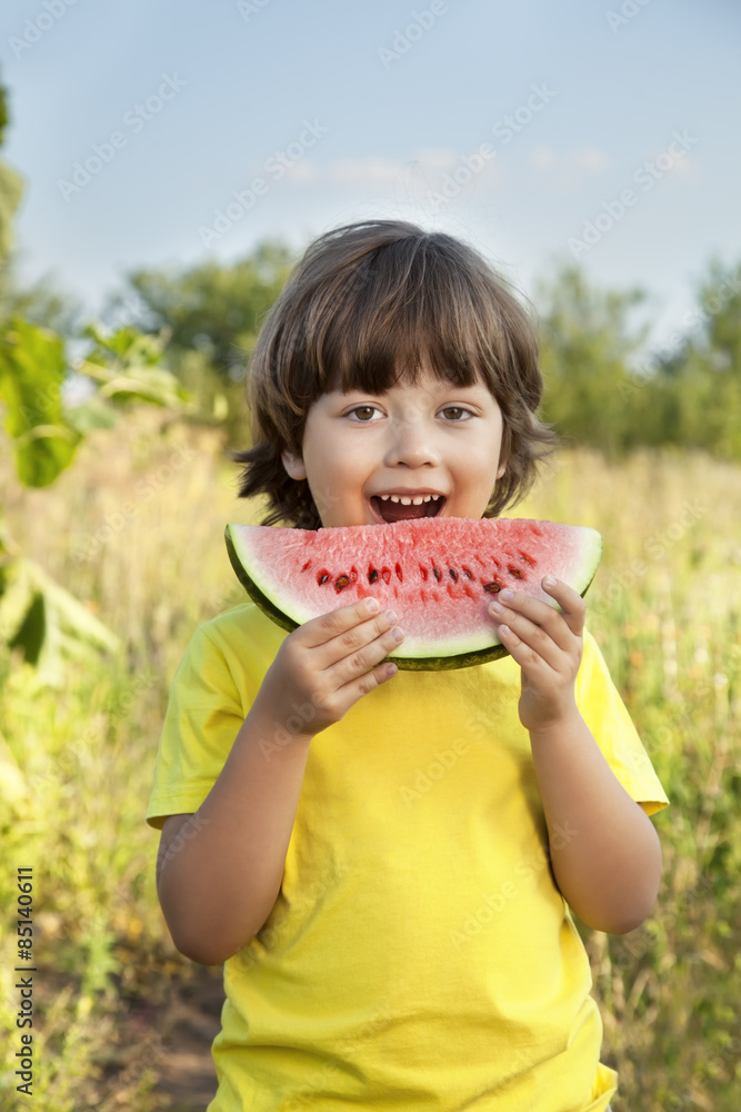Fototapeta premium happy child eating watermelon in the garden