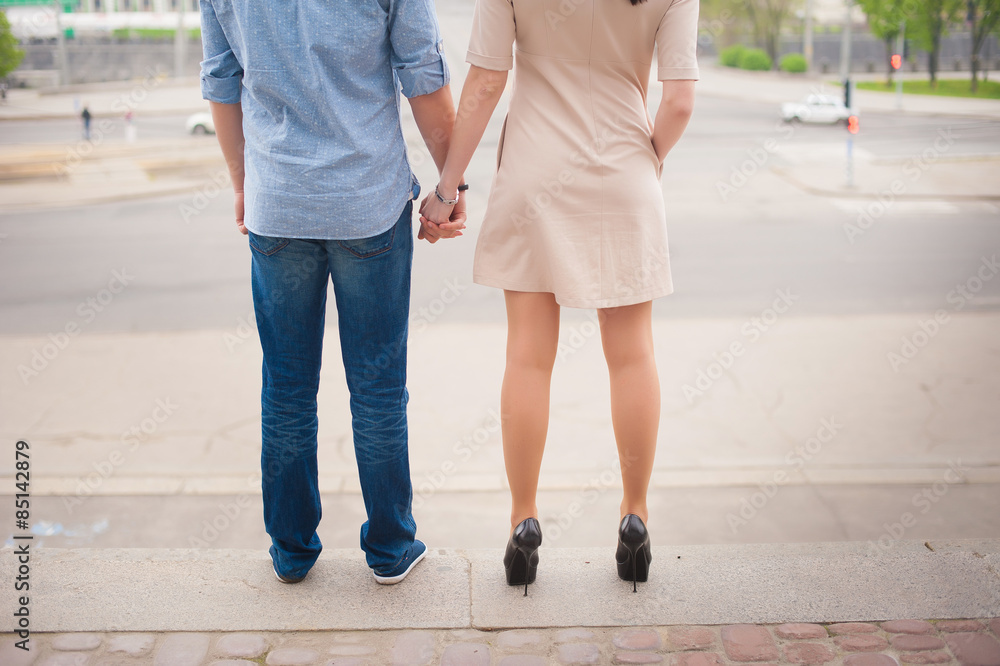 Beautiful stylish young couple standing and holding hands on a background of a big city, love, dating, lifestyle, romance Beautiful stylish young couple standing and holding hands on a background of a big city, love, dating, lifestyle, romance