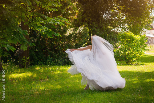 Beautiful young bride in a magnificent wedding dress spinning in nature, happiness, fun
