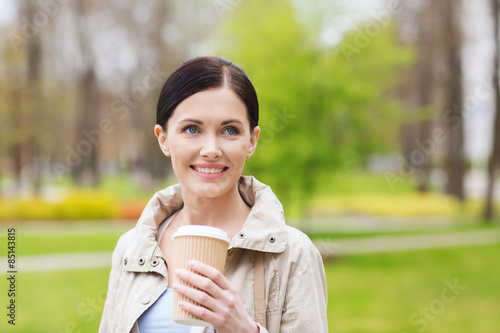 smiling woman drinking coffee in park