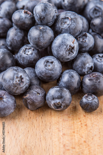 Blueberry fruits in a white bowl on wooden board background